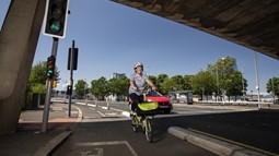 Case study Claire Griffin cycling her folding bike on new segregated cyclepath in Belfast - Middlepath Street, Belfast with red car passing in background
