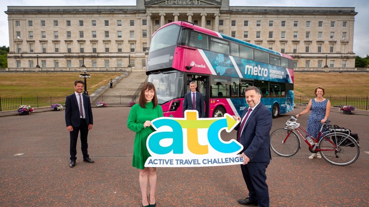 Active Travel Launch in front of Stormont Buildings with Infrastructure Minister Nichola Mallon and Health Minister Robin Swan holding a large ATC cutout, David Tumility Public Health Agency, Chris Conway Translink and Caroline Bloomfield, Sustrans pictured in the background with a bus and bicycle